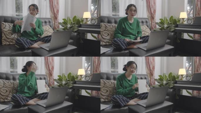 宽镜头和手持镜头有吸引力的亚洲少女使用笔记本电脑视频会议与她的同学就他们的演示项目集思广益。在线家庭