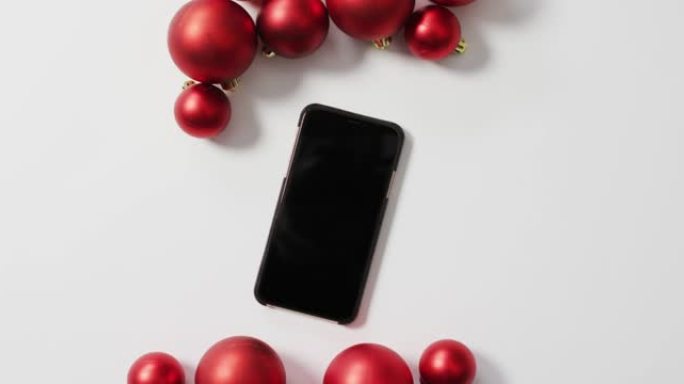 白色背景上的红色圣诞小玩意和智能手机视频