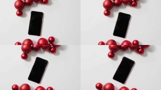 白色背景上的红色圣诞小玩意和智能手机视频