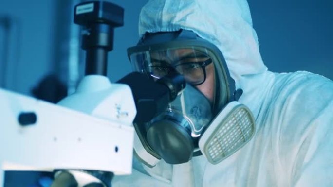 穿着防溅服的男科学家正在显微镜下观察