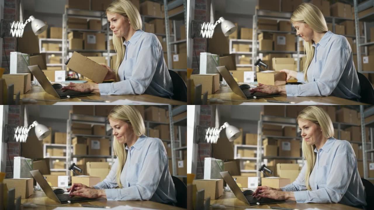 快乐的客户支持经理使用笔记本电脑检查包裹上的订单号，准备一个小纸板箱进行邮资。在仓库工作的金发女小企