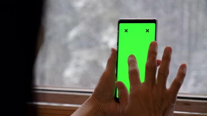 在降雪时手持绿色屏幕的智能手机