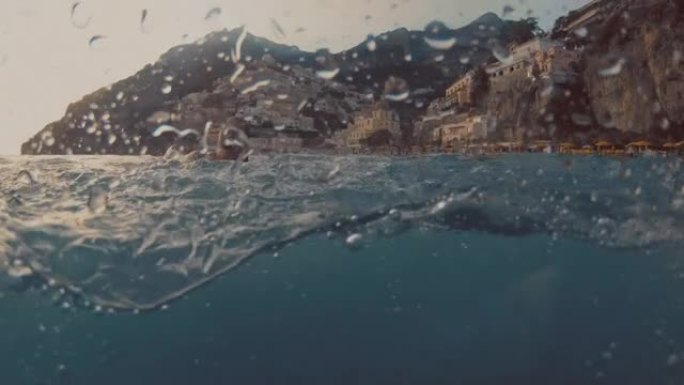 懒人欣喜若狂的女人在著名村庄波西塔诺的海湾游泳