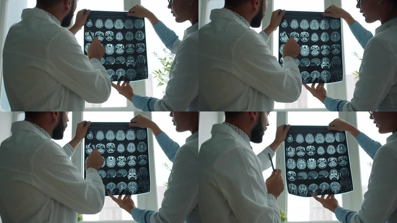 男性和女性医务人员持有和研究MRI图像在医院讨论病例