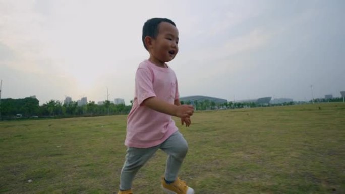 日落时在草原上奔跑的男婴