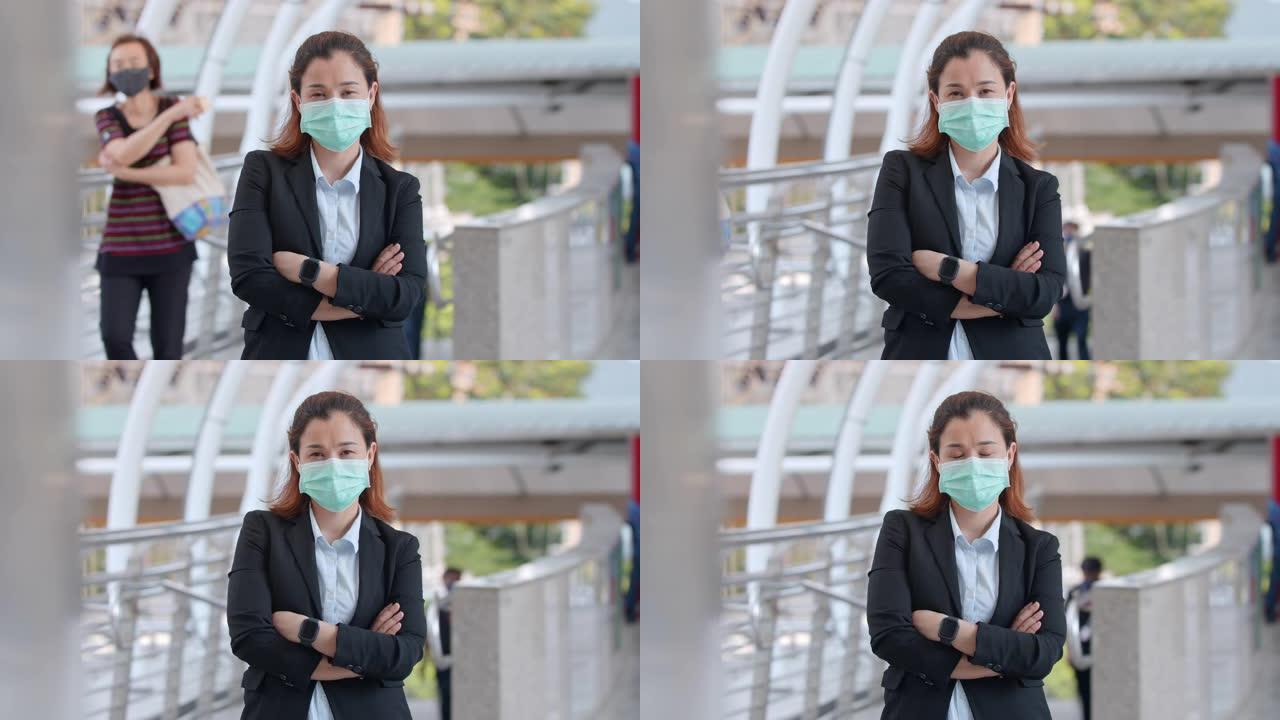 戴着防护口罩的商业女性在城市站着并双臂交叉，慢动作
