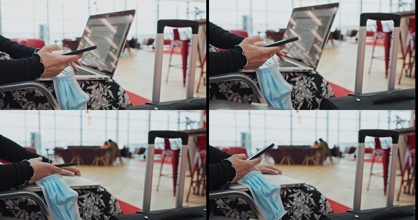 女人双手拿着手机和笔记本电脑在机场休息室