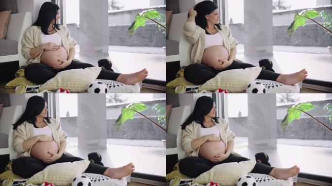 DS孕妇坐在家里的地板上爱抚她的肚子