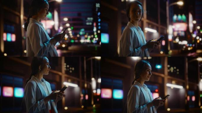 美丽的年轻女子使用智能手机走过充满霓虹灯的夜晚城市街道。微笑的女性使用手机进行在线购物，社交媒体发布