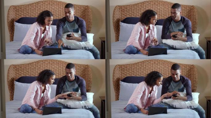 年轻的黑人夫妇坐在床上，网上比较购物