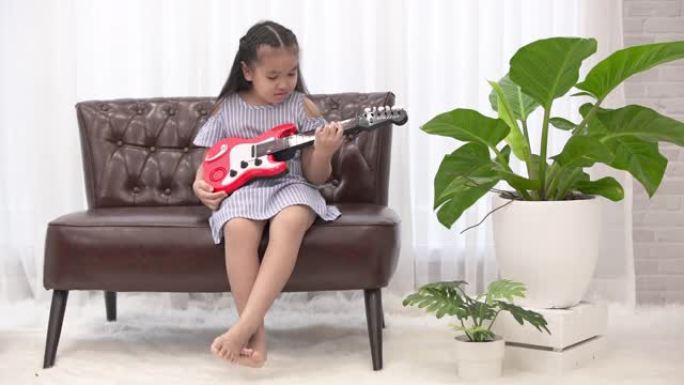 可爱的小女孩在客厅玩吉他玩具