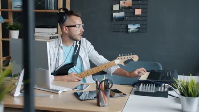 才华横溢的家伙在工作室室内演奏乐器键盘和吉他录制音乐