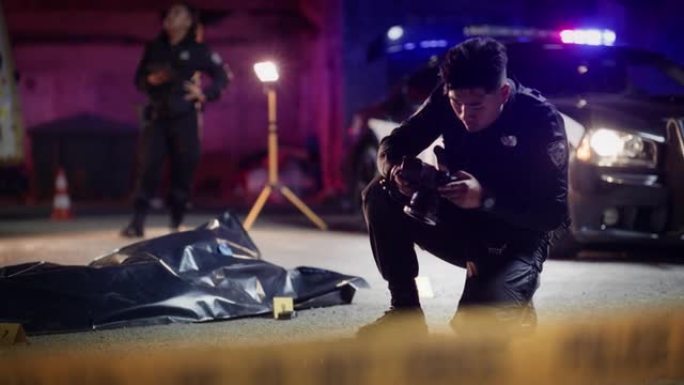 广角肖像拍摄的亚洲年轻警察做法医工作和拍摄标记证据的照片。犯罪现场调查组与护理人员在幕后合作