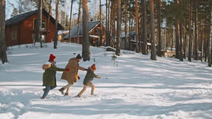 幸福的三口之家在乡下的雪地里奔跑