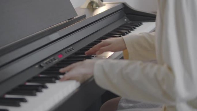 特写亚洲少女用音乐弹奏钢琴电话会议。通过互联网上的视频通话播放。可爱的女孩玩电钢琴玩得开心。音乐家青