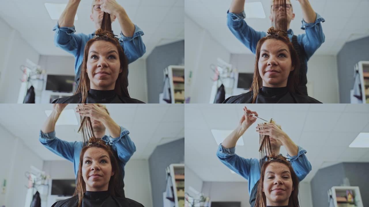 慢动作发型师在沙龙梳理和切割女性头发
