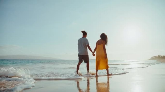 海滩上的日落漫步享受生活情侣走在沙滩上涨
