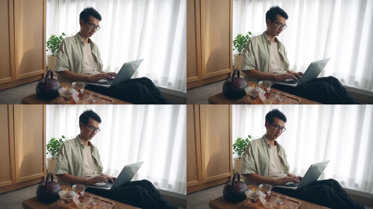 亚洲男子在家中使用笔记本电脑