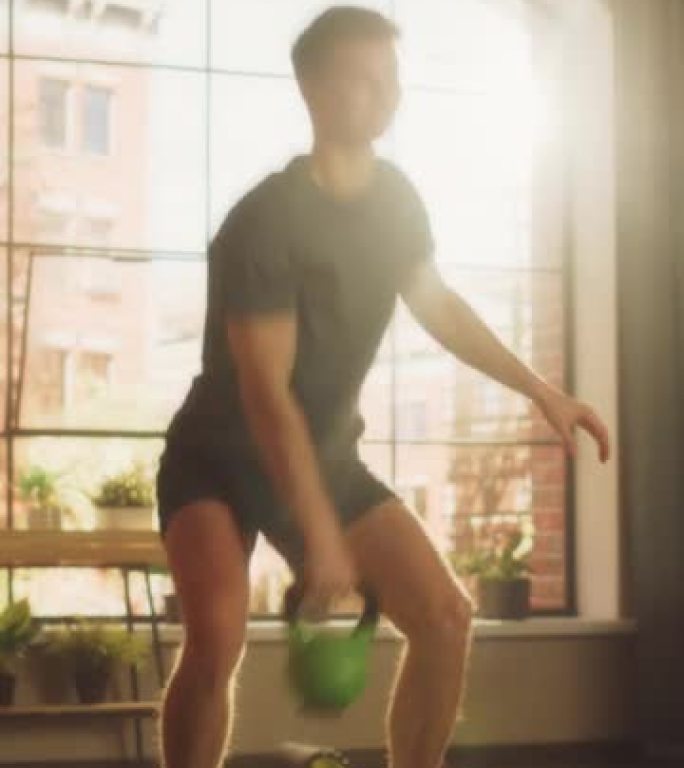 垂直屏幕: 运动健美的人从手到手挥动沉重的壶铃，在阳光公寓的家中进行晨练时进行核心强化锻炼。健康和健