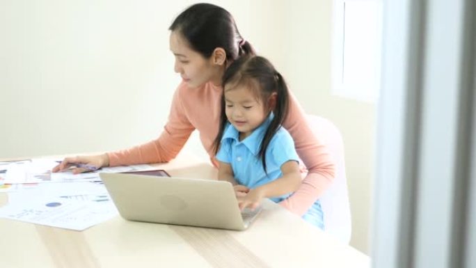 母亲带着笔记本电脑和女儿在家工作
