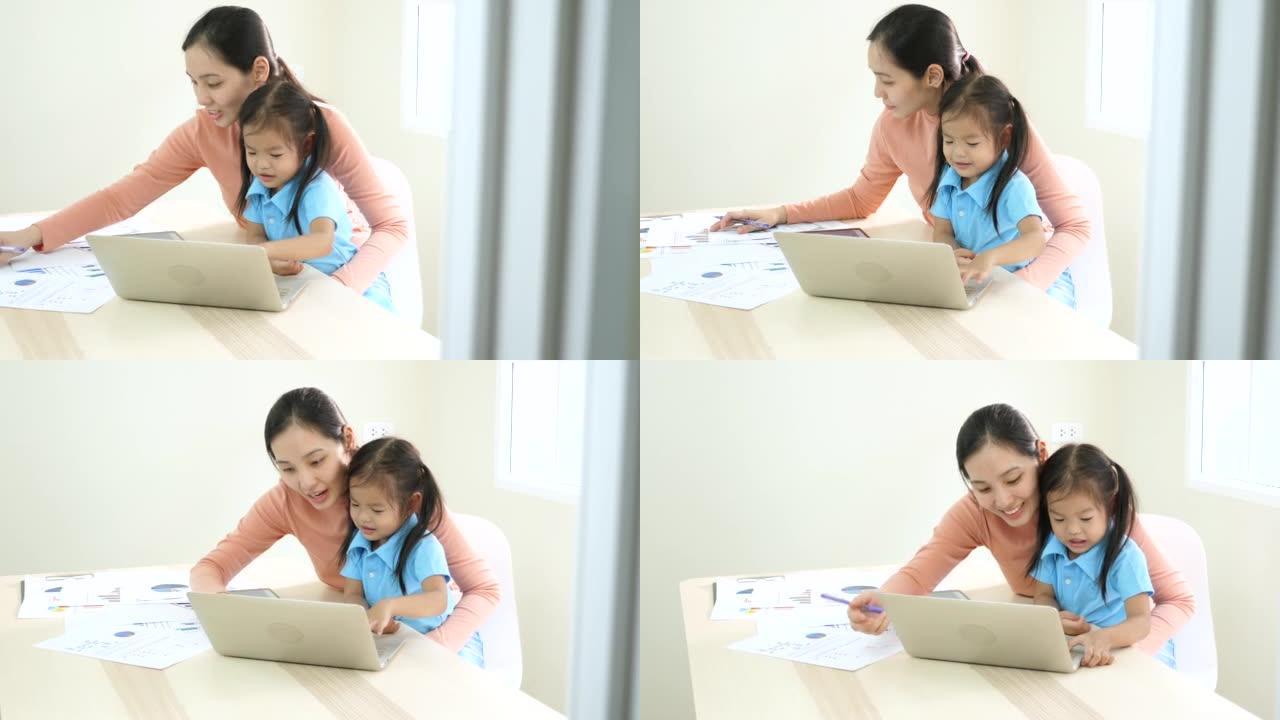 母亲带着笔记本电脑和女儿在家工作