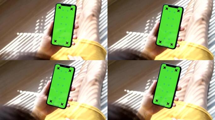 女性手中的绿屏模板智能手机在家里的镜头