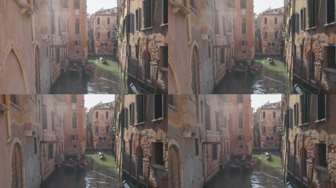 在旧房屋中狭窄的运河中拍摄了两个吊船。意大利威尼斯。典型的威尼斯运河，清晨有吊船