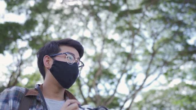 戴着口罩的亚洲男子使用胶片相机拍摄大自然中的树