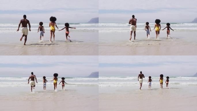 非裔美国父母和两个孩子在海滩上奔跑