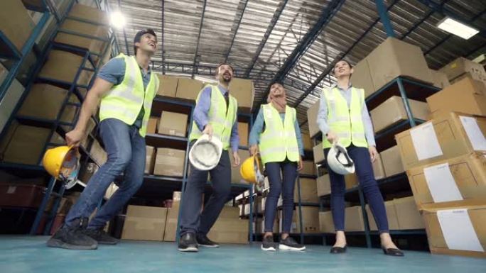 慢动作FHD: 仓库工人和经理的跨种族团队在完成工作后将头盔扔向空中庆祝。用于商业仓库和庆祝概念。