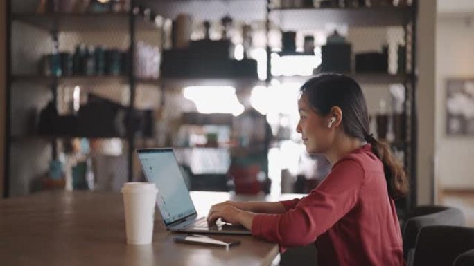 亚洲妇女在咖啡店使用笔记本电脑工作