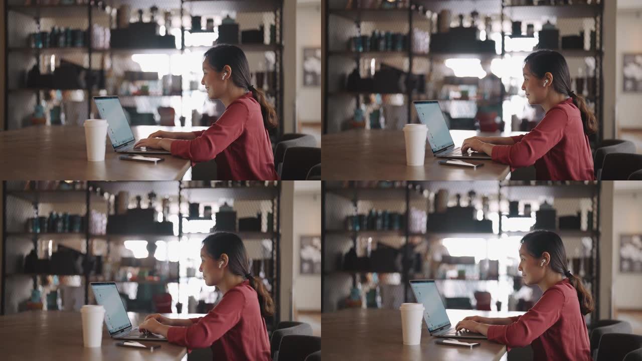 亚洲妇女在咖啡店使用笔记本电脑工作