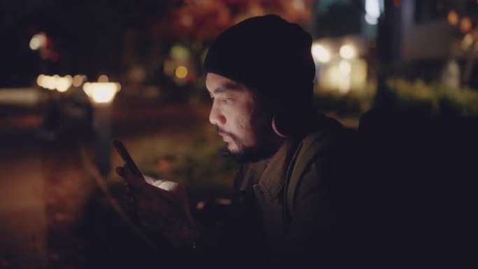 亚洲男子自由职业者晚上在城市地区使用智能手机。