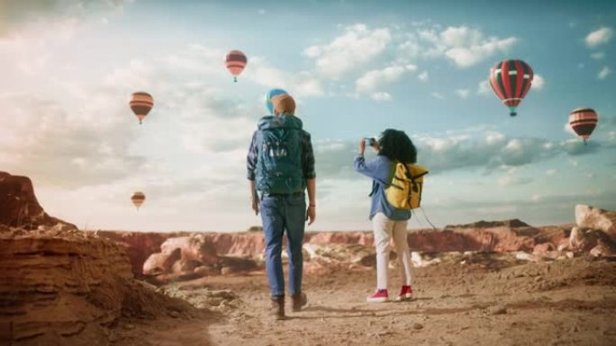年轻的多样化旅游夫妇带着背包在落基峡谷谷的大荒野徒步旅行。女背包客在山区国家公园热气球节的智能手机上