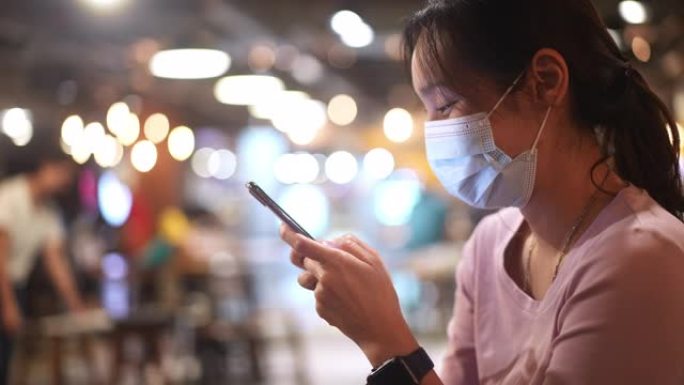 亚洲女性使用带面罩的智能手机