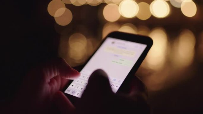 CU女人晚上在黑暗的海滩上用智能手机发短信