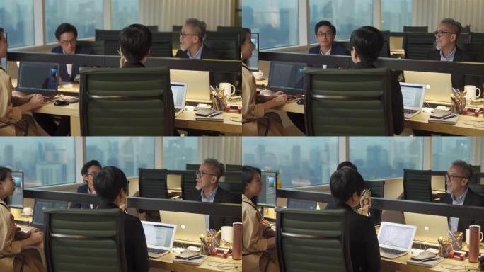 4个成熟的亚洲华裔白领在办公室工作站工作和交流