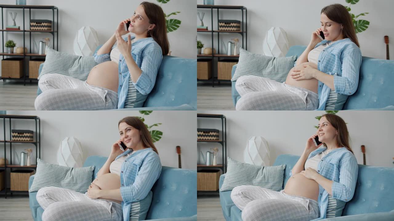 怀孕女孩在手机上聊天在家室内抚摸肚子的慢动作