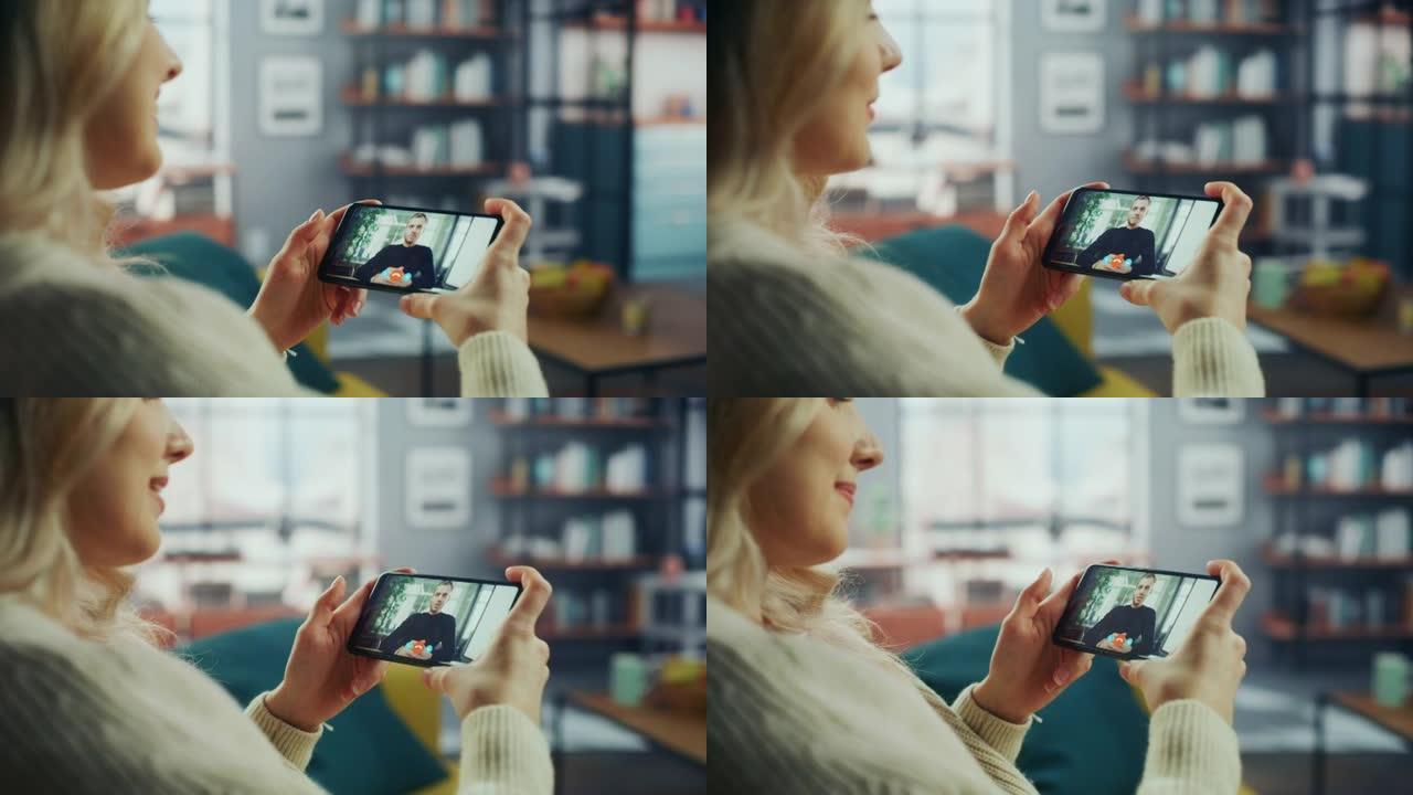 一名女性在客厅的智能手机上与她英俊的白人男性朋友在视频通话中聊天的特写镜头。自由职业者通过互联网与办