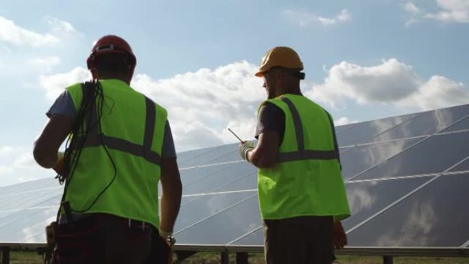 男工程师在太阳能电池板附近行走并与同事交谈