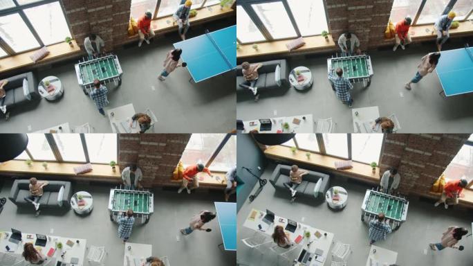 在现代办公空间中，同事在室内玩桌上足球和乒乓球的俯视图