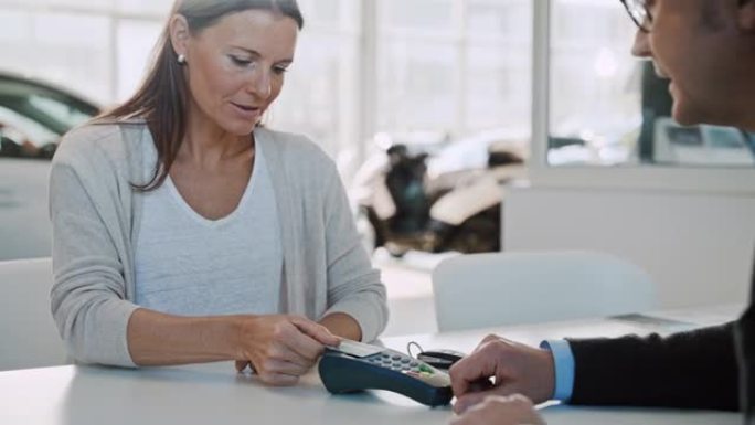 SLO MO成熟的女人使用她的信用卡为新车进行非接触式付款