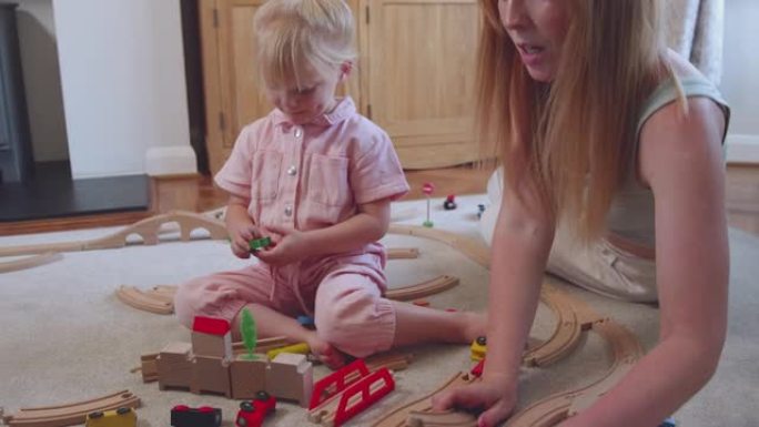 母女在家玩地毯上的木制火车玩具