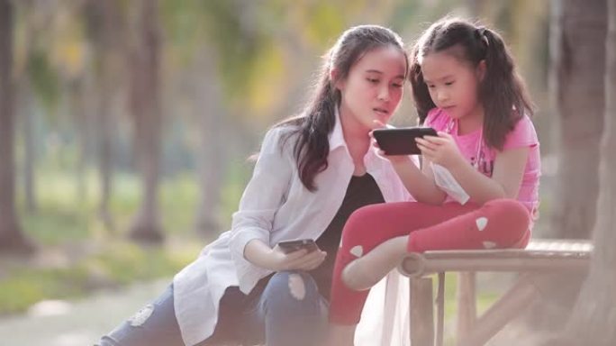 在公共公园使用手机的亚洲儿童女孩