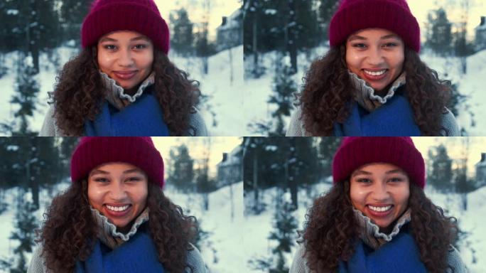 冬天的心情。在白雪皑皑的森林慢动作中，快乐的年轻美丽的混血女人在镜头前微笑的肖像。