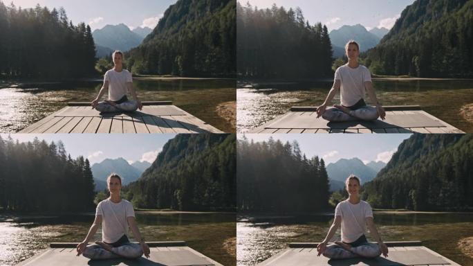 成年女性，金发碧眼，坐在jezersko湖前的木板路上，沉思着她的瑜伽马特