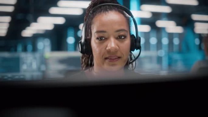 呼叫中心办公室: 友好的非裔美国女性技术客户支持专家的肖像在耳机上交谈，使用计算机。客户体验官通过视