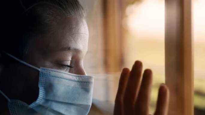 戴着面具的SLO MO女人透过窗户看，回想起新型冠状病毒肺炎禁闭期间的自由