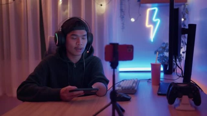 残疾的亚洲男性esport玩家在霓虹灯的房间里用智能手机玩激动人心的游戏。
