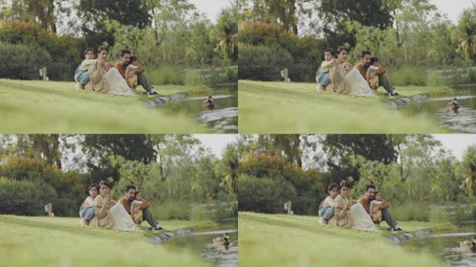 双胞胎小孩和妈妈和爸爸坐在湖边玩耍。